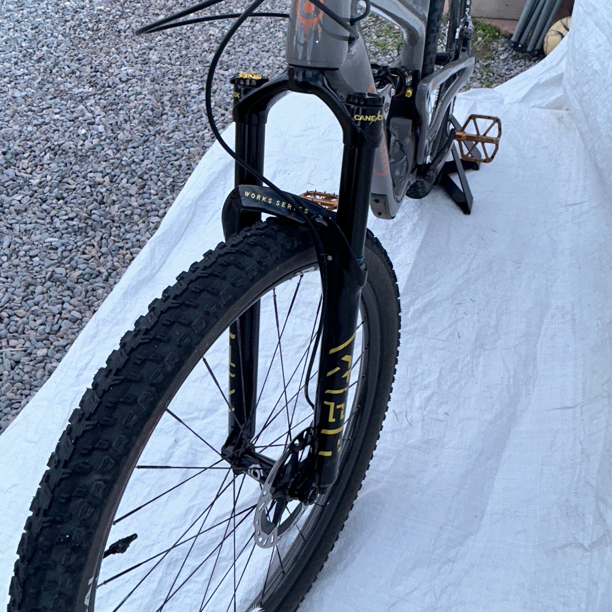 Bicycle with a close-up of the front wheel and suspension fork on a snowy ground.