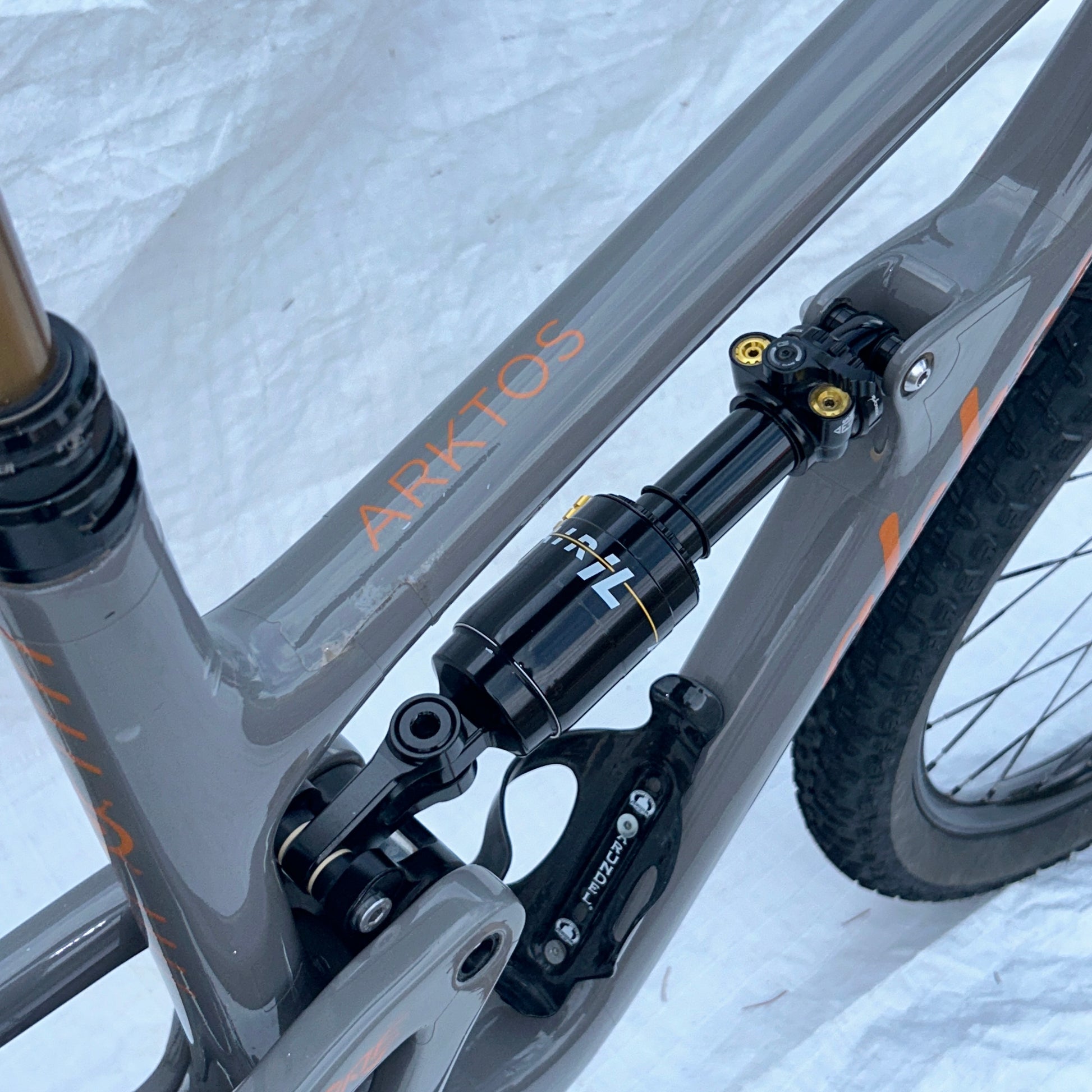 Close-up of a bicycle frame with 'ARKTOS' branding on a snowy background